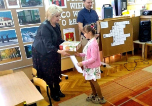 Uczennica z grupy przedszkolnej odbiera dyplom oraz nagrodę za udział w konkursie.