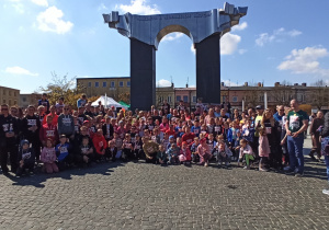 Wszyscy uczestnicy biegu z różnych szkół pozują do zdjęcia grupowego na rynku miasta.