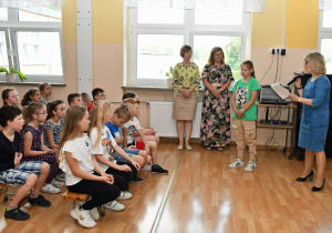 Grupka uczniów słucha opowieści swojej koleżanki o urodzinowym baloniku.