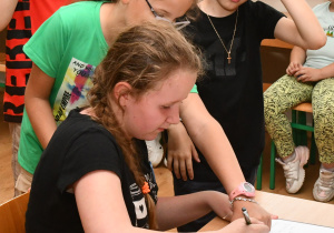 Uczniowie czekają w kolejce do księgi pamiątkowej w celu złożenia podpisów.