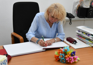 Pani Dyrektor dokonuje wpisu do księgi pamiątkowej.