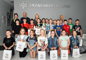 Uczniowie z wychowawczynią oraz Panią Dyrektor, a także z przedstawicielami Urzędu Miejskiego w Piątku pozują do grupowego zdjęcia.
