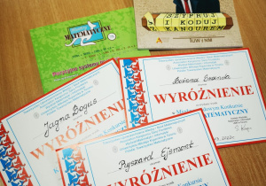 Na stole leżą dyplomy za otrzymane wyróżnienie oraz nagrody książkowe.