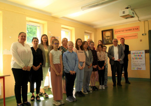 Laureaci konkursu wraz z nauczycielami oraz organizatorami konkursu pozują do zdjęcia grupowego. W tle na ścianie obraz Janusza Korczaka.