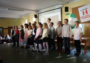 Klasa trzecia śpiewa piosenkę dla nauczycieli podczas przedstawienia z okazji Dnia Edukacji Narodowej.