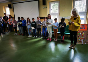 Uczniowie wyróżnieni i nagrodzeni w konkursie różańcowym prezentują się przed społecznością szkolną podczas apelu. Pani Dyrektor wyczytuje nazwiska uczniów.
