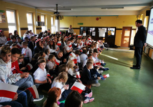 Nauczyciel historii przemawia do uczniów na widowni.
