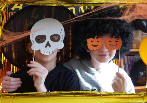 Uczniowie na tle dekoracji Halloweenowej pozują do zdjęcia.