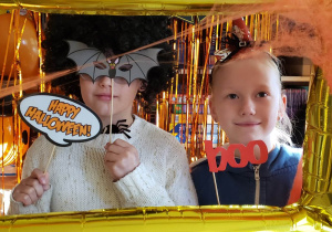 Uczennice pozują do zdjęcia w ramce z gadżetami Halloweenowymi.