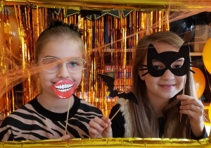 Uczennice pozują do zdjęcia w balonowej ramce z gadżetami Halloweenowymi.