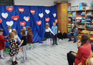 Przedszkolaki tańczą w parach dla zgromadzonych babć i dziadków.
