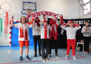 Uczniowie w strojach narodowych skandują sportowe okrzyki.