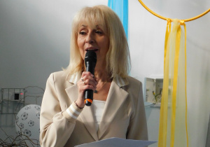 Pani Dyrektor przemawia do publiczności na sali gimnastycznej.