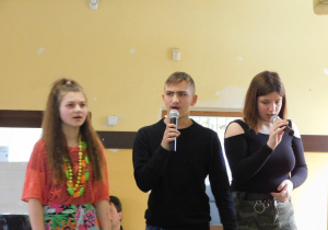 Dwie uczennice wraz z kolegą śpiewają piosenkę.