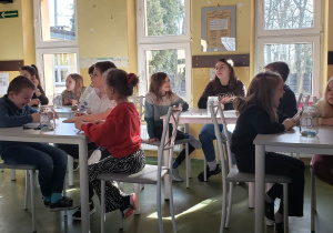 Grupa uczniów siedzi przy stoliku rozwiązując wspólnie zadanie matematyczne.