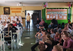 Uczniowie na korytarzu szkolnym przyglądają się reprezentantom klas biorących udział w konkursach matematycznych.