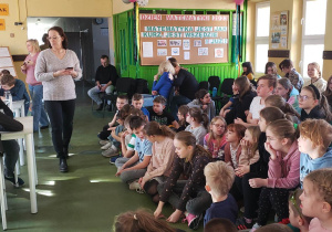 Uczniowie na korytarzu szkolnym przyglądają się reprezentantom klas biorących udział w konkursach matematycznych.