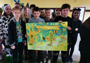 Uczniowie klasy czwartej prezentują plakat na powitanie wiosny.
