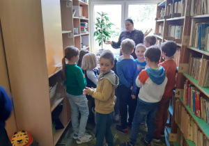 Uczniowie między półkami w bibliotece szkolnej.