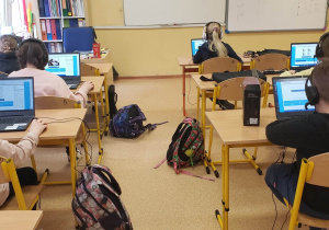 Uczniowie przy komputerach rozwiązują zadania konkursowe.