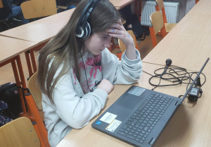 Uczennica przy komputerze rozwiązuje zadania konkursowe.