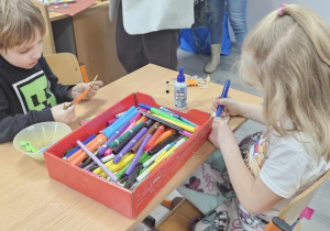 Chłopiec z dziewczynką wykonują pracę plastyczną.