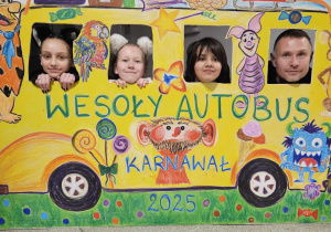 Uczennice wraz z nauczycielem pozują do zdjęcia w makiecie zatytułowanej Wesoły Autobus.