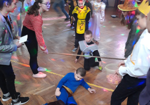 Dzieci przechodzą pod bardzo nisko zawieszoną poprzeczką.
