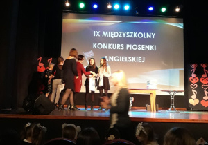 Uczennice odbierają nagrody na scenie.