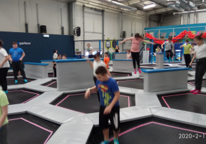 Dzieci skaczą na trampolinach.