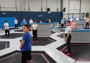 Dzieci skaczą na trampolinach.