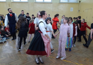 Organizatorzy spotkania w śląskich strojach ludowych tańczą z uczniami.