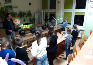 W pracowni przyrodniczej dzieci oglądają globus, lunetę i wiatraki.