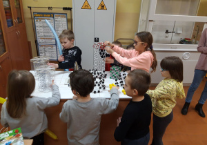 W pracowni chemicznej dzieci oglądają modele sieci i cząsteczek.