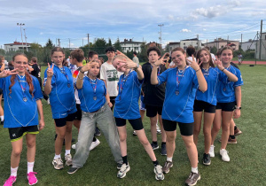 Drużyna piłkarska dziewcząt i chłopaków pozuje do zdjęcia w strojach reprezentacji szkoły.