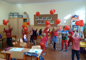 Dzień bez Przemocy. Dzieci ubrane na czerwono bawią się czerwonymi balonami.