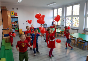 Dzień bez Przemocy. Dzieci ubrane na czerwono bawią się czerwonymi balonami.