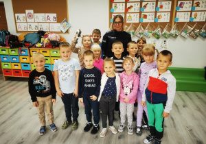 Uczniowie klasy przedszkolnej pozują do zdjęcia z panią policjantką.