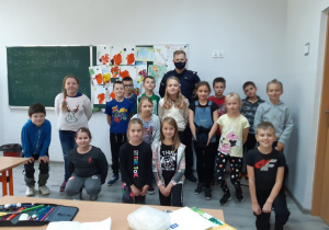 Uczniowie klasy trzeciej pozują do zdjęcia z panem policjantem po zakończonych zajęciach.