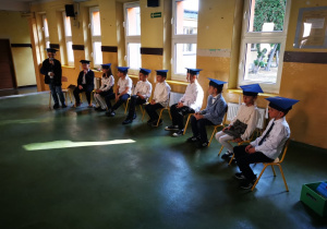 Uczniowie klasy pierwszej stoją przed punlicznością w odświętnych strojach, prezentując przygotowany program artystyczny.