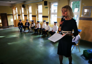 Pani Dyrektor przemawia do zgromadzonych osób na holu szkolnym.
