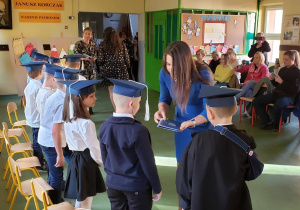 Wychowawczyni klasy pierwszej wręcza każdemu uczniowi pamiątkę ślubowania.