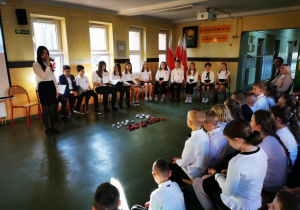 Grupa odświętnie ubranych uczniów prezentuje przygotowany program artystyczny z okazji 11 listopada.