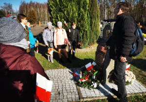 Uczniowie klasy 5 wraz z opiekunami gromadzą się przy pomniku poświęconym wszystkim walczącym o niepodłegość Polski.