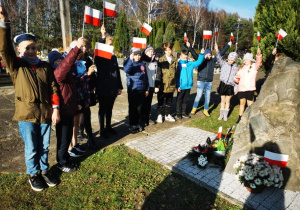 Uczniowie klasy 5 wraz z opiekunami gromadzą się przy pomniku poświęconym wszystkim walczącym o niepodłegość Polski.