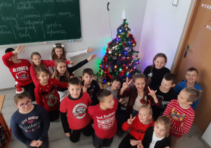 Uczniowie klasy trzeciej pozują do zdjęcia, w tle widać udekorowaną choinkę.