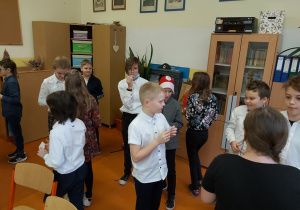 Uczniowie łamią się opłatkiem.