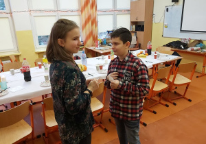 Uczniowie łamią się opłatkiem. W tle widać wigilijny stół.