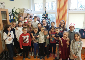 Uczniowie klasy piątej i pierwszej pozują do zdjęcia grupowego na tle choinki.