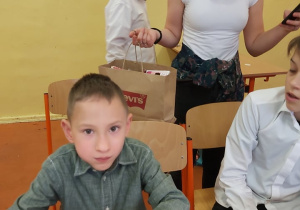 Chłopiec siedzi przy stole z udekorowanym piernikiem.